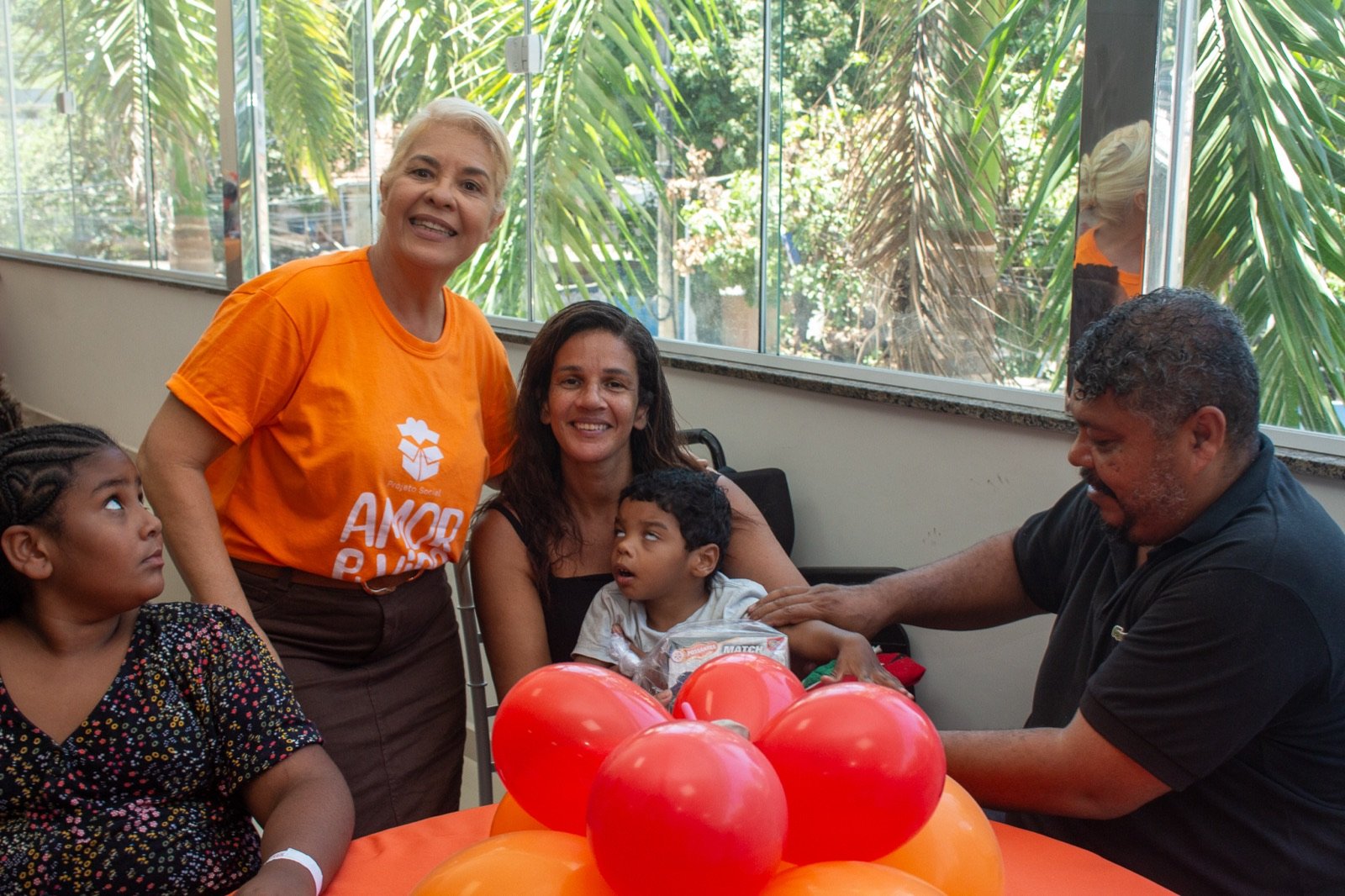 Voluntária ao lado de mãe e filho especial acolhidos pelo projeto