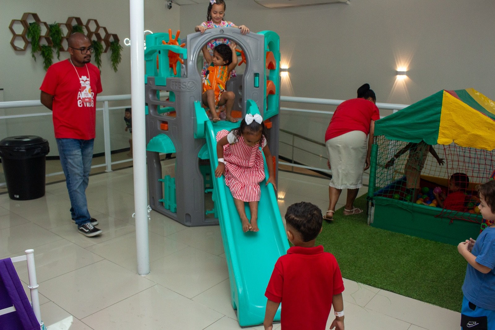 Crianças brincando no escorregador e na piscina de bolinhas