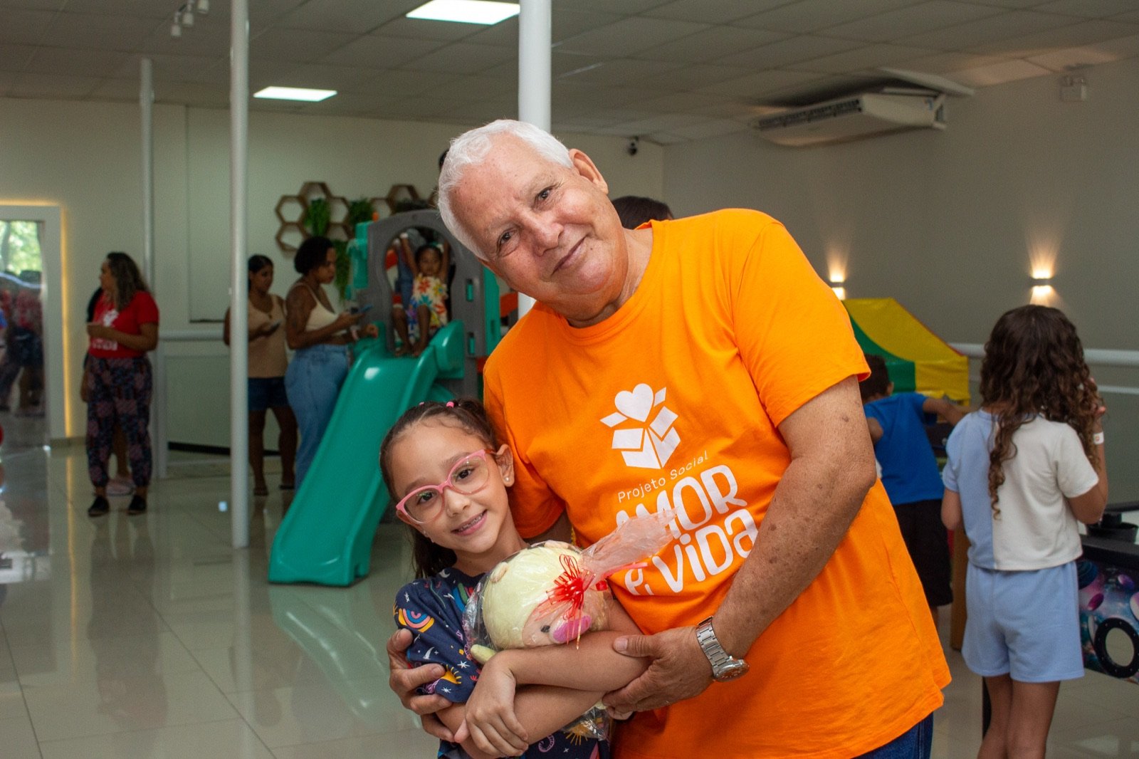 Padrinho abraçando a afilhada com o presente de pelúcia