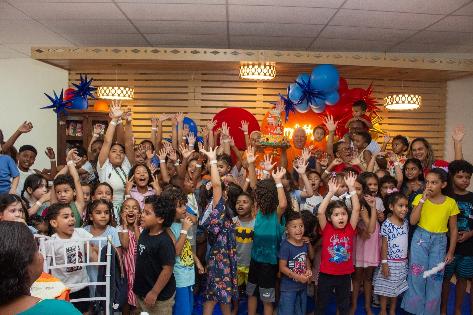 Crianças e voluntários do Amor e Vida com as mãos para o alto comemorando