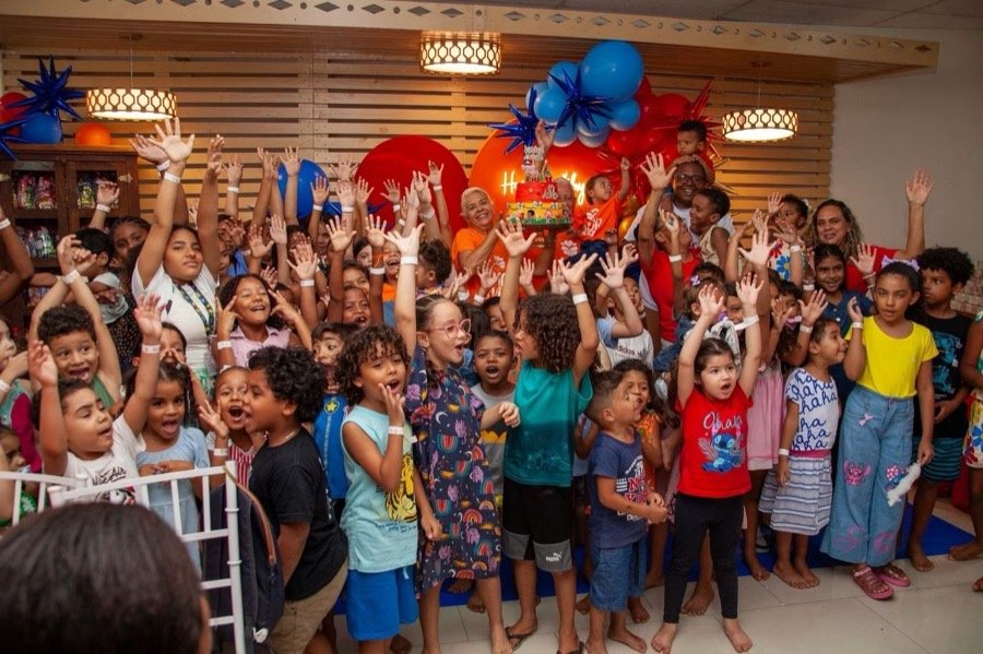 Crianças e voluntários com as mãos levantadas comemorando os 10 anos do Amor e Vida