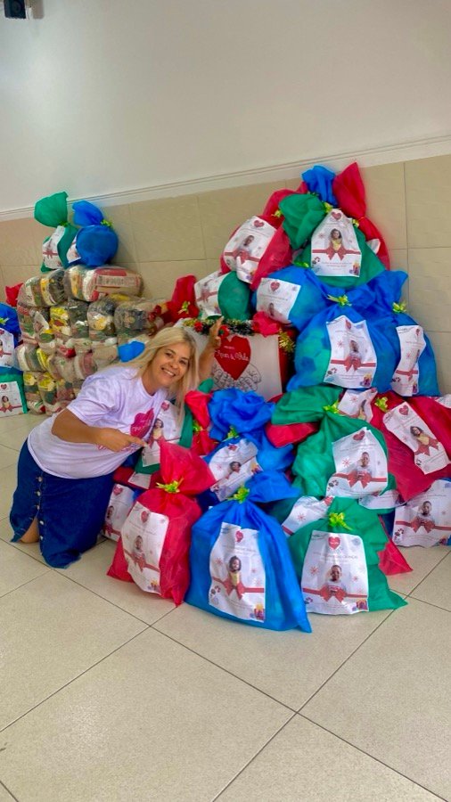 Voluntária ao lado de dezenas de sacolas de presente prontas para entrega